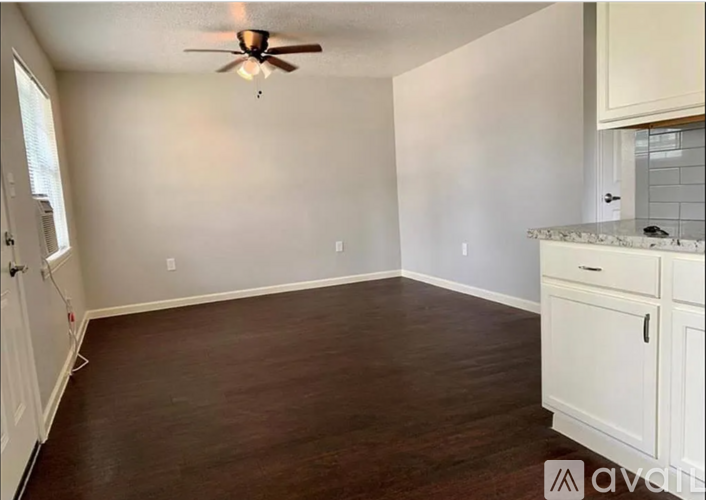 A room with a ceiling fan and wooden flooring.