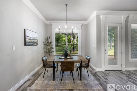 A dining room with a table set for four and a view of a green lawn through the window.