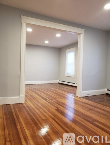 A room with wooden flooring and a white doorway leading to another room.