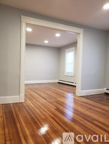 A room with wooden flooring and a white doorway leading to another room.