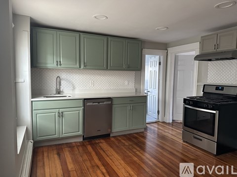 A kitchen with green cabinets and a black stove top oven.