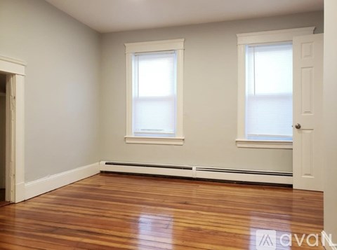 A room with wooden floors and two windows.