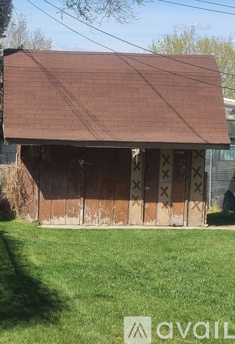 A small building with a brown roof and a fence in front of it.