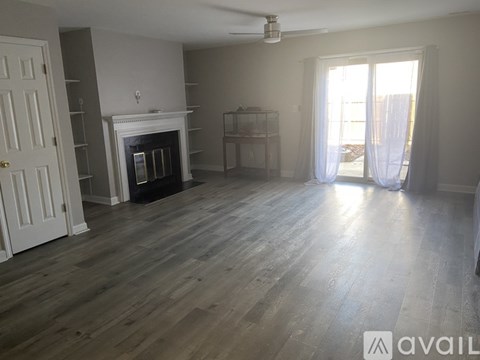 A spacious living room with a fireplace and wood flooring.