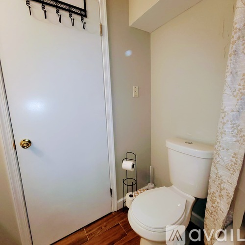 A white toilet in a small bathroom with a white door and a towel rack on the wall.