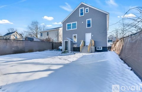 A house with a grey exterior is surrounded by a snowy landscape.