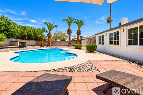 A pool surrounded by palm trees and a patio area.