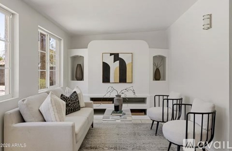 A living room with a white couch, a coffee table, and a large abstract painting on the wall.