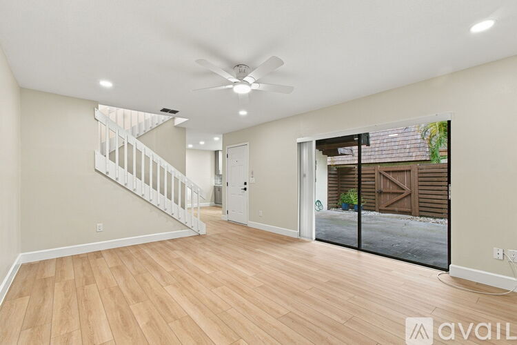 A spacious room with wooden flooring and a ceiling fan.
