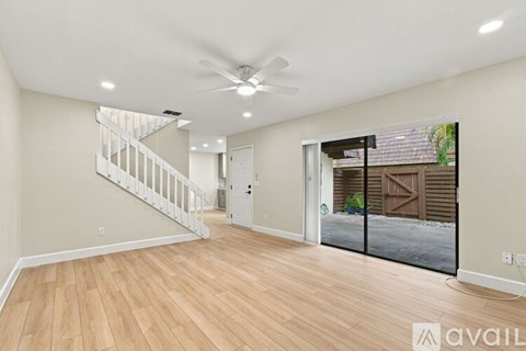 A spacious room with wooden flooring and a ceiling fan.