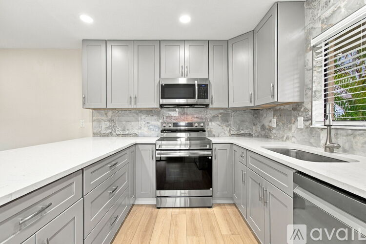 A kitchen with grey cabinets and a stainless steel oven.