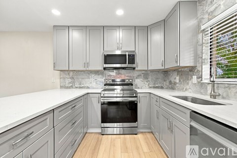 A kitchen with grey cabinets and a stainless steel oven.