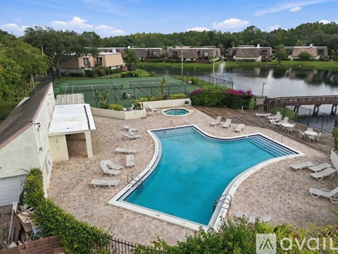 A pool surrounded by chairs and a tennis court in the background.