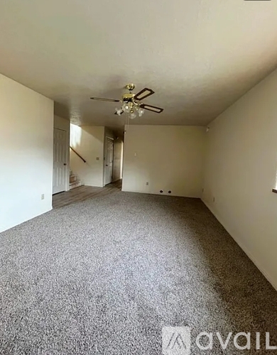 A spacious room with a ceiling fan and carpeted floor.