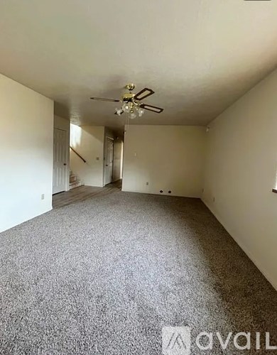 A spacious room with a ceiling fan and carpeted floor.