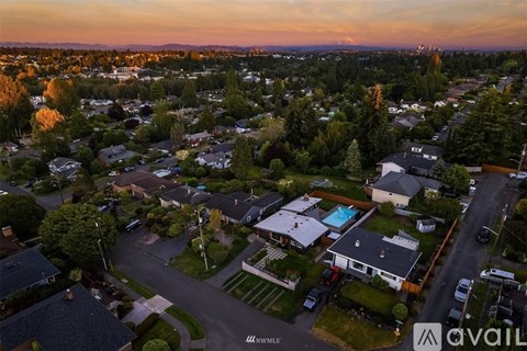 A neighborhood with houses and a street with cars.