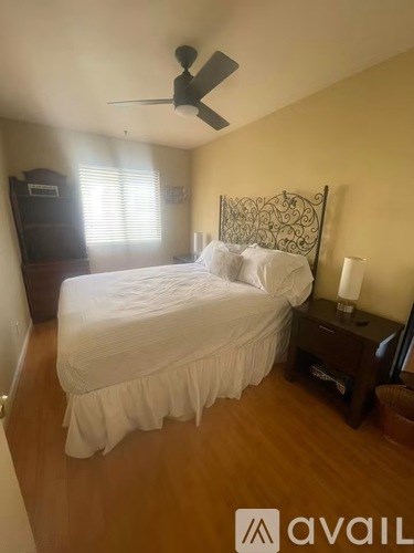 A bedroom with a bed, nightstand, and a ceiling fan.