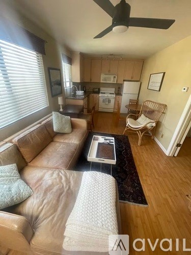 A living room with a brown leather couch and a ceiling fan.