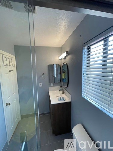 A bathroom with a sink, mirror, and a glass shower door.
