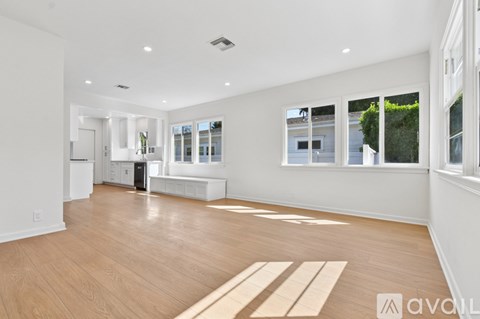 A spacious living room with wooden flooring and large windows.