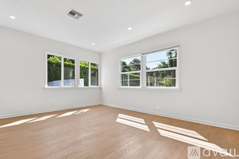 A spacious room with wooden flooring and large windows.