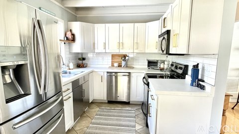 A kitchen with white cabinets and a stainless steel refrigerator.