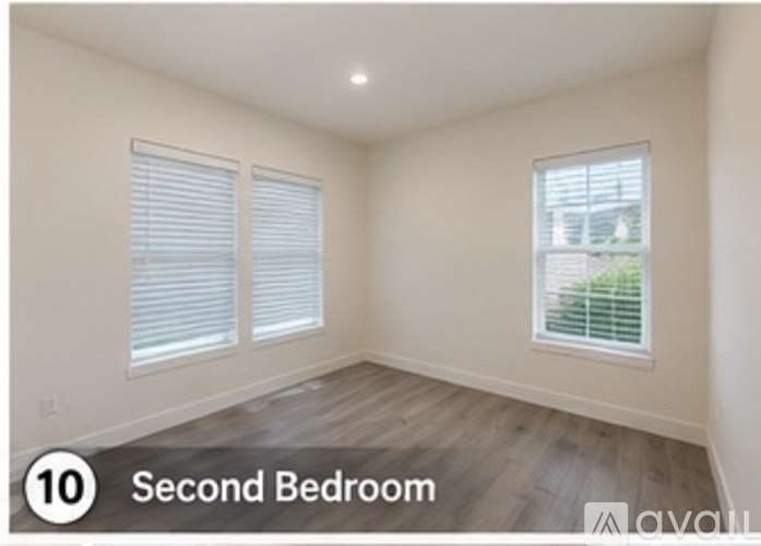 A second bedroom with wood flooring and a window with blinds.