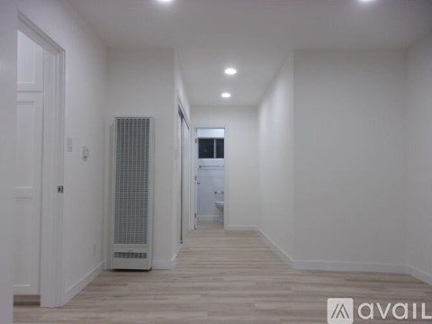 A long hallway with a white door and a white wall.