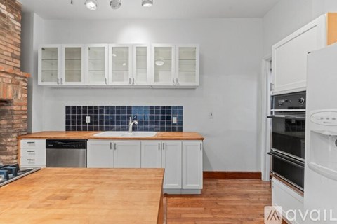 A kitchen with white cabinets and a wooden island.