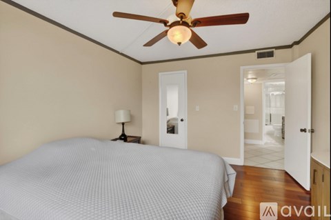A bedroom with a bed, a ceiling fan, and a door leading to another room.