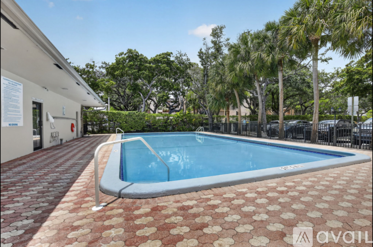 A pool surrounded by a brick patio and palm trees.
