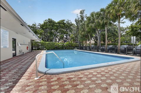 A pool surrounded by a brick patio and palm trees.
