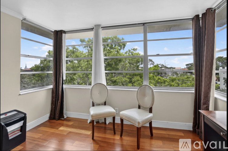 Two chairs are placed in front of a window with a view of trees and buildings outside.