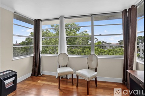 Two chairs are placed in front of a window with a view of trees and buildings outside.