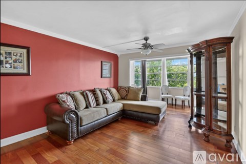 A living room with a brown leather couch and a wooden floor.