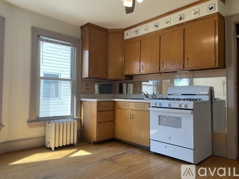 A kitchen with wooden cabinets and a white stove top oven.
