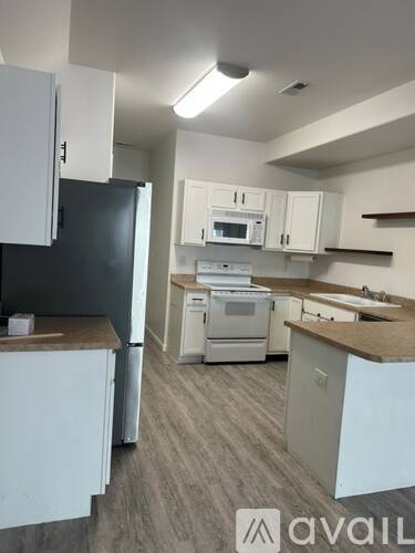 A kitchen with white cabinets and a black fridge.