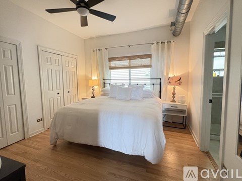 A bedroom with a large bed and a ceiling fan.