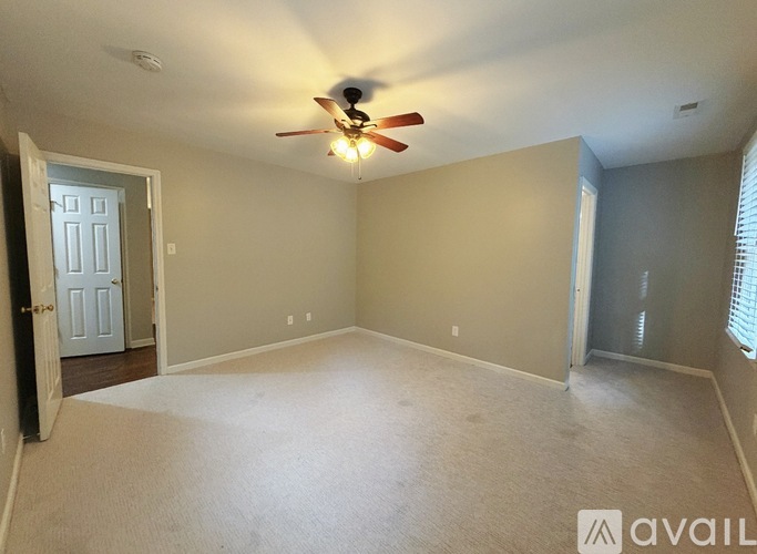 A spacious room with a ceiling fan and carpeted floor.
