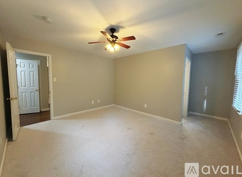 A spacious room with a ceiling fan and carpeted floor.