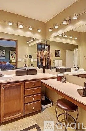A well-lit, spacious bathroom with a vanity, mirrors, and a stool.