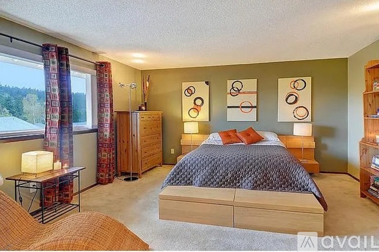 A bedroom with a large bed and a window with curtains.