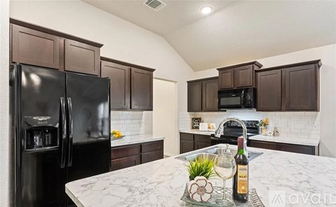 A kitchen with a black fridge and brown cabinets.