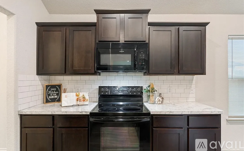 A kitchen with dark brown cabinets and a black stove top oven.