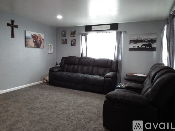 A living room with a black leather couch and a wooden coffee table.
