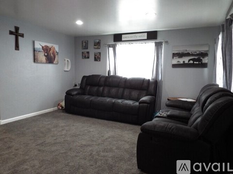 A living room with a black leather couch and a wooden coffee table.