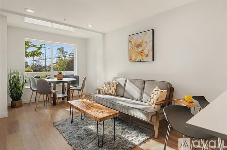 A living room with a grey couch, a coffee table, and a dining table with chairs.