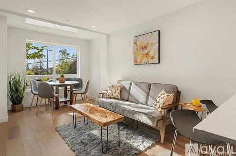 A living room with a grey couch, a coffee table, and a dining table with chairs.