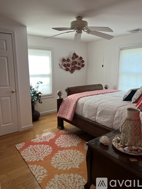 A bedroom with a bed, a ceiling fan, and a rug on the floor.