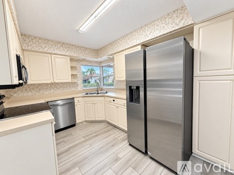 A kitchen with a stainless steel refrigerator and white cabinets.